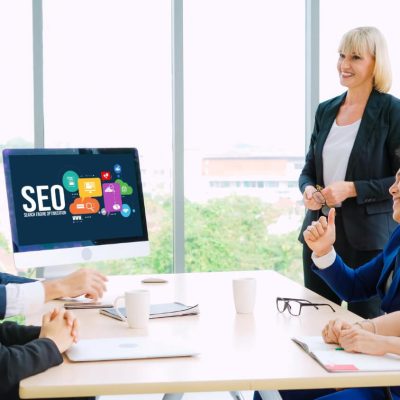 Professionals in a meeting with an SEO presentation on the computer screen.